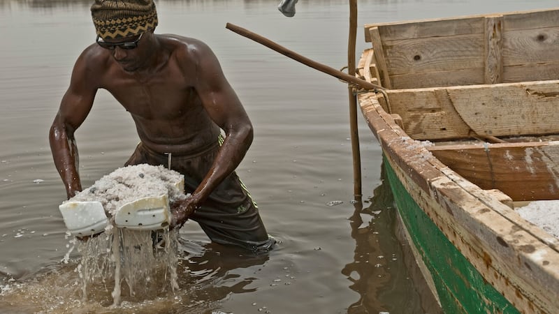 Two plastic containers are used by a harvester to scoop salt from the bottom of Lake Retba/Lac Rose in Senegal. Photograph: Lar Boland