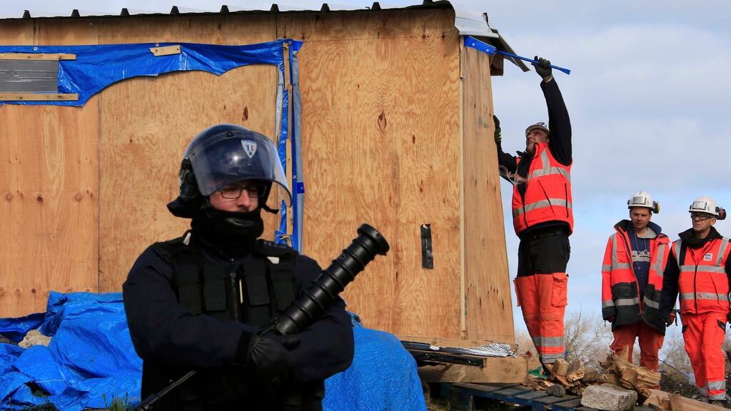 A French riot policeman secures the area as workmen destroy a makeshift shelter during the partial dismantlement of the camp for migrants called the “jungle”, in Calais, northern France. Photograph: Pascal Rossignol/Reuters