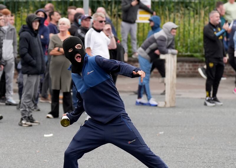 A protester throws a bottle towards Garda officers after a number of fires were started in Coolock. Photograph: Niall Carson/PA Wire