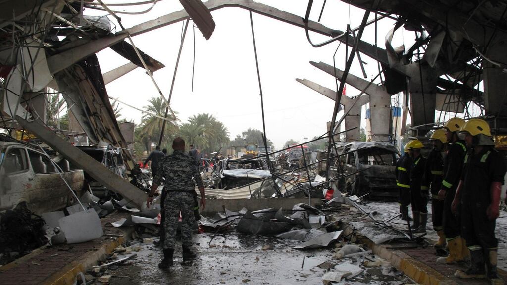 Iraqi security forces and firefighters inspect the site of a suicide attack in the city of Hilla. Photograph: Reuters/Habib