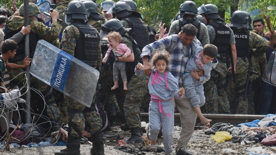A member of the Macedonian special police forces holds a baby (C) as migrants try to cross into Macedonia near the southern city of Gevgelija on Saturday. Photograph: Georgi Licovski/EPA