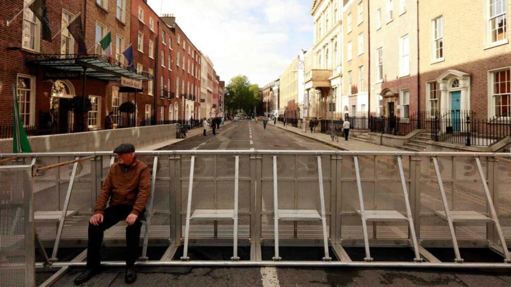 A man sits on barriers erected to keep demonstrators away from Leinster House during the announcement of the 2015 Budget