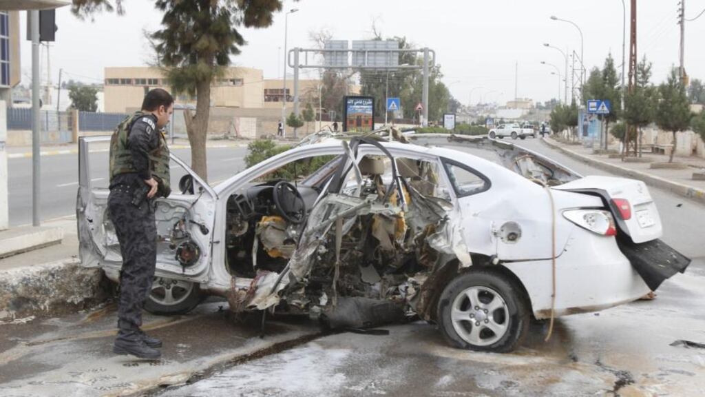 A member of the Iraqi security forces inspects a car after a bomb in Kirkuk, 250km north of Baghdad yesterday. Photograph: Ako Rasheed/Reuters.