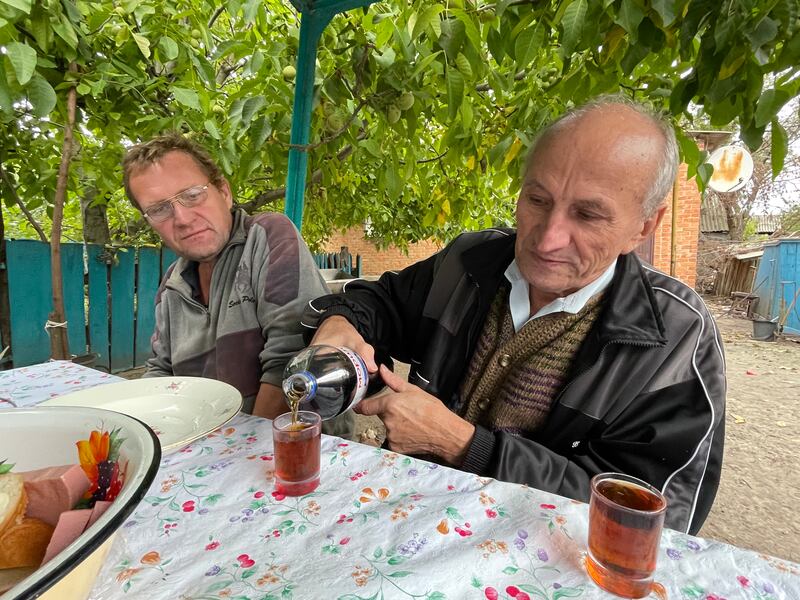 Petro Pivovar pours homemade brandy for son Andriy and friends, after Petro and wife Klavdiya returned to their cottage in the village of Mospanove, northeastern Ukraine. The region was fully liberated from Russian troops this month. Andriy spent four months alone in the cottage under near-daily shelling. Photograph: Daniel McLaughlin