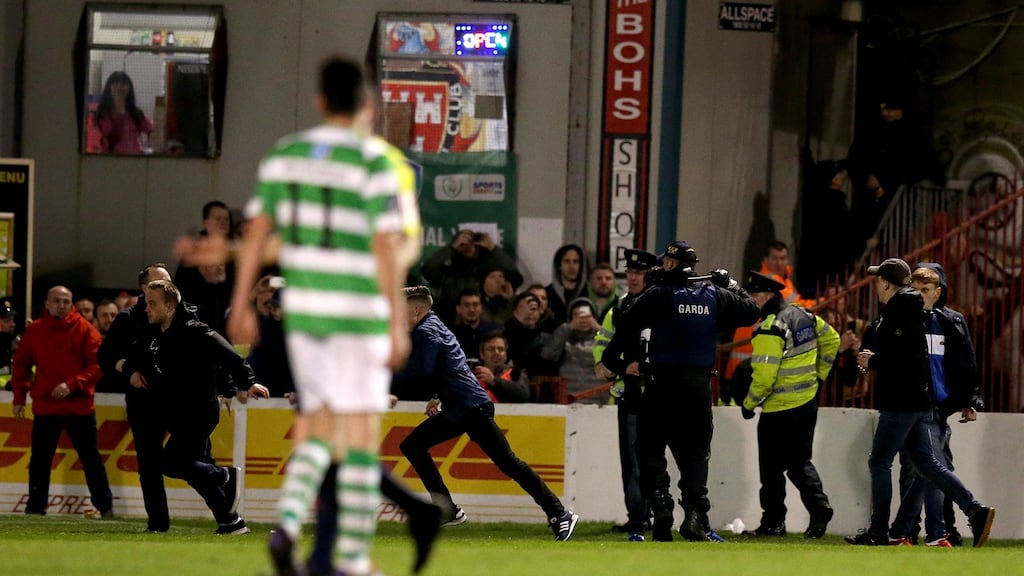 Gardai try to quell the on-pitch trouble as Bohemians fans run back to the Jodi Stand during their 4-0 loss to Shamrock Rovers. Photo: Ryan Byrne/Inpho