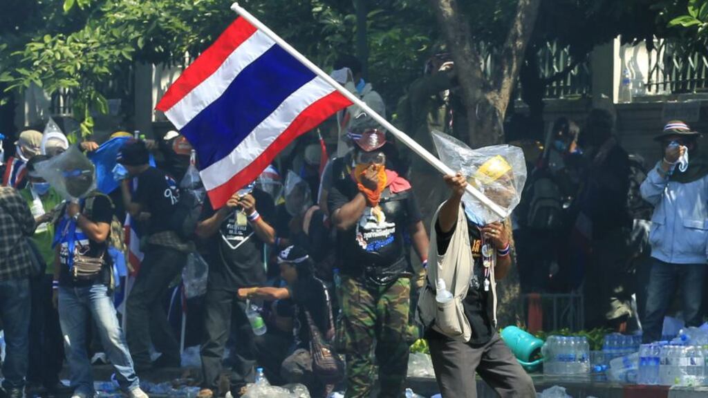 A Thai anti-government protester waves a Thai flag in a face off with riot police officers as the demonstrators try and reach to the Metropolitan Police Bureau in Bangkok, Thailand, today. Photograph: Narong Sangnak/EPA.