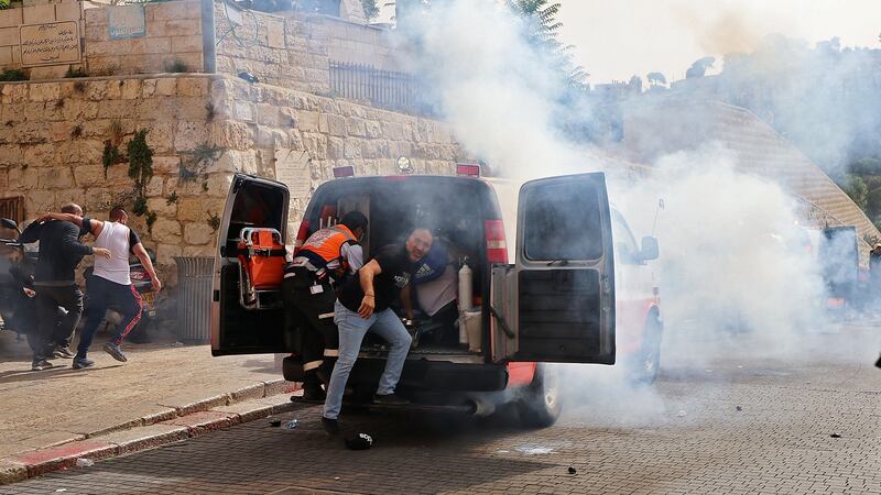 Palestinian medics evacuate wounded protesters as Israeli security forces fire tear gas in Jerusalem’s Old City on Monday. Photograph: Emmanuel Dunand/AFP via Getty Images