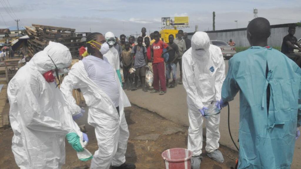 Health workers spray each other with disinfectant after they removed the body of a woman suspected of dying from Ebola in Monrovia, Liberia, yesterday.