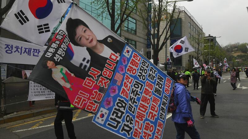 A supporter of South Korea’s former president Park Geun-hye carries pictures her during a rally in Seoul on Friday. Photograph: Getty Images
