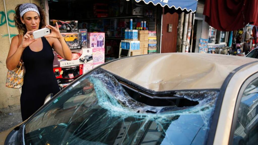 A woman takes a photograph of a car damaged when debris from a rocket intercepted by Israel landed in a Tel Aviv street yesterday. Photograph: Finbarr O’Reilly/Reuters