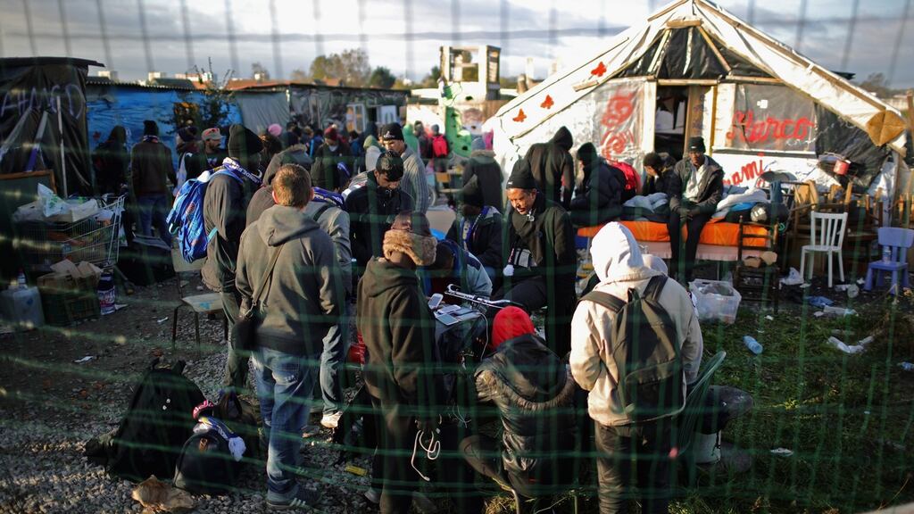 Migrants including minors wait outside the Calais “Jungle” schoolhouse after being allowed back inside to shelter on Friday. Photograph: Getty Images