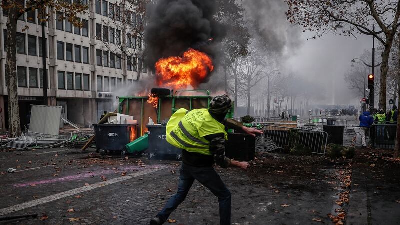 Protesters wearing yellow vests  clash with riot police near a burning barricade during a demonstration over high fuel prices on the Champs Elysee in Paris on Saturday. Photograph: EPA