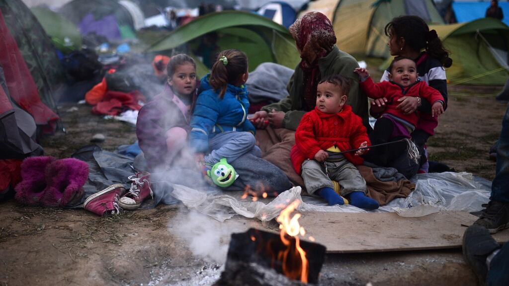 Migrants warm-up by a fire at a makeshift camp along the Greek-Macedonian border near the village of Idomeni. More than 5,000 people were trapped at the Idomeni camp after four Balkan countries announced a daily cap on migrant arrivals. Slovenia and Croatia, both EU members, and Serbia and Macedonia said they would restrict the number of daily arrivals to 580 per day. Photograph: Louisa Gouliamakilouisa/Getty Images