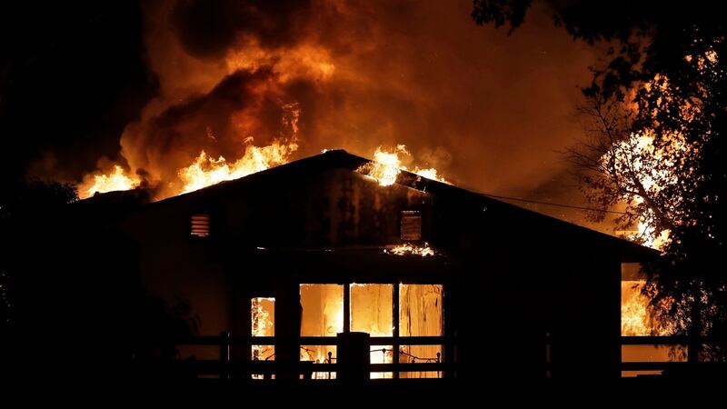 A home burns  in  wildfires  in Santa Clarita, California. Fast-growing fires across California have forced thousands of people to evacuate. Photograph: AP