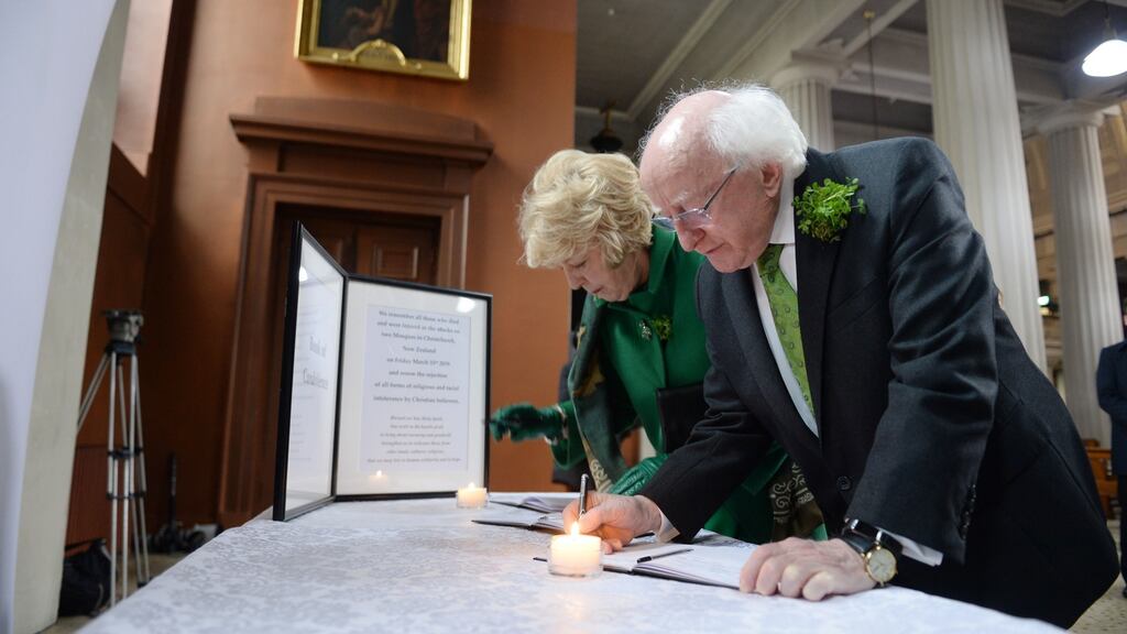President Higgins and his wife Sabina sign a book of condolence at the Pro Cathedral for victims of the New Zealand shootings. Photograph: Dara MacDonaill