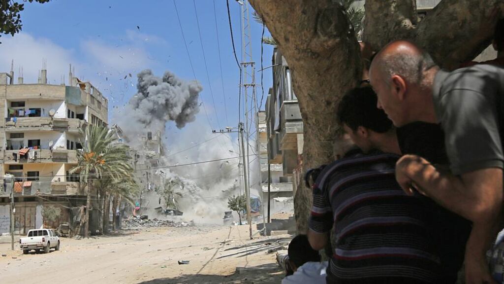 Palestinians take cover as smoke rises after Israeli warplanes targeted a house in the Al-Shatea refugee camp in the west of Gaza City yesterday. Photograph: EPA/Mohammed Saber