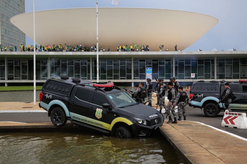 A police vehicle crashes into a fountain as supporters of Brazilian former president Jair Bolsonaro invade the National Congress in Brasilia on Sunday. Photograph: Sergio Lima/AFP