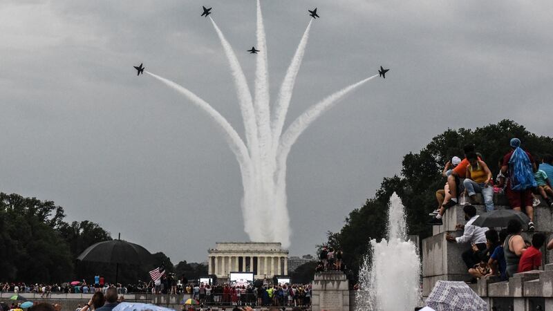 People react to a military fly over on the National Mall while  Donald Trump gives his speech during 4th of July festivities o in Washington. Photograph:  Stephanie Keith/Getty Images