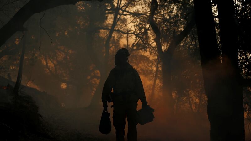 A firefighter brings supplies to crewmates, while working to control a wildfire in Sonoma, California. Photograph: Jim Urquhart/Reuters