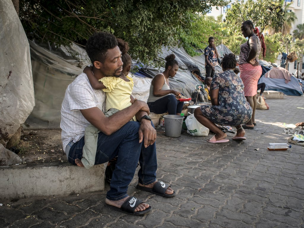 A man comforts his daughter at a camp for migrants in front of the International Organization for Migration offices in Tunis, Tunisia. Many African migrants find themselves stranded in Tunisia, unable to move on. Photograph: Laura Boushnak/The New York Times