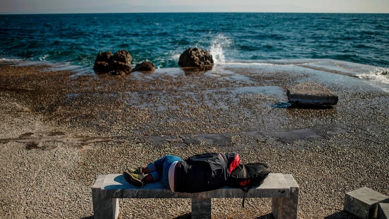 A migrant sleeps on a bench at the harbour quay on Lesbos. Photograph: Angelos Tzortzinis/AFP via Getty Images