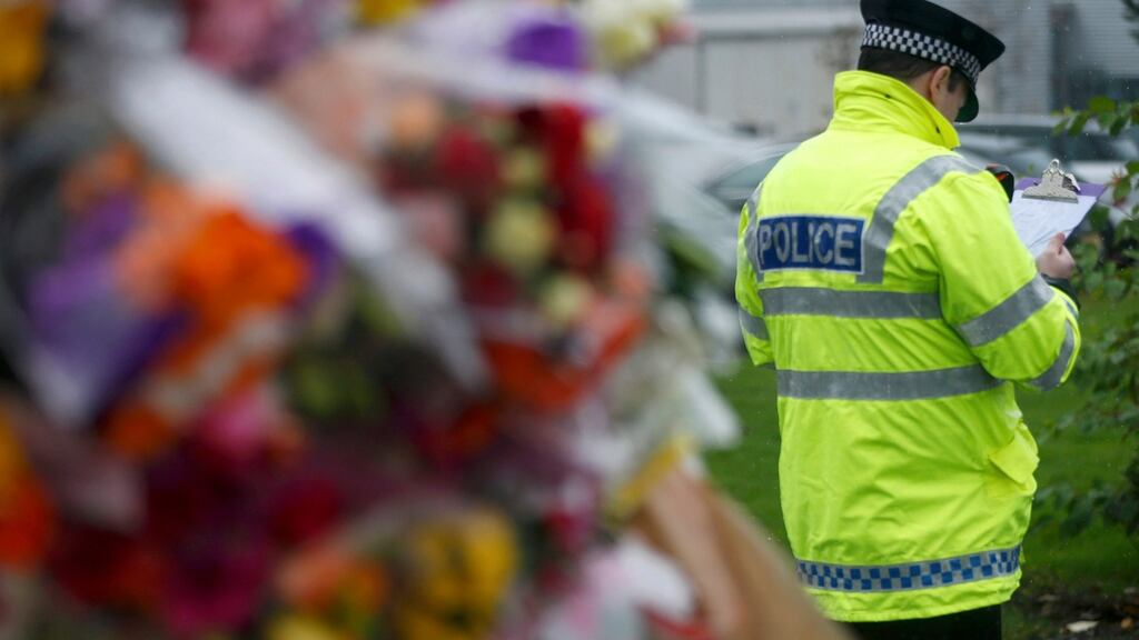 A policeman stands beside floral tributes at the gates of Cults Academy Aberdeen, Scotland. Photograph: Reuters