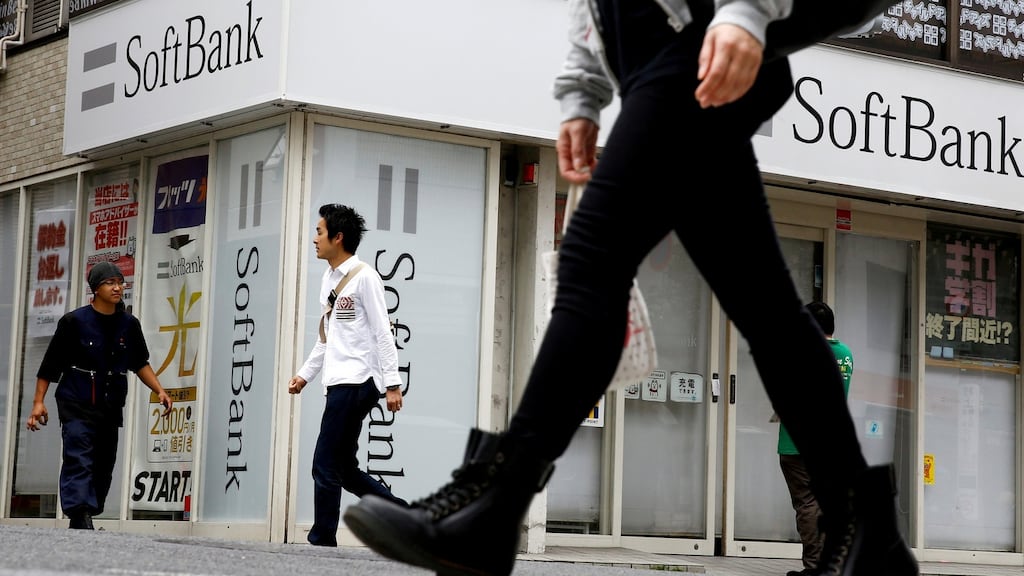 People walk past a retail shop of the SoftBank telecommunications company in Tokyo