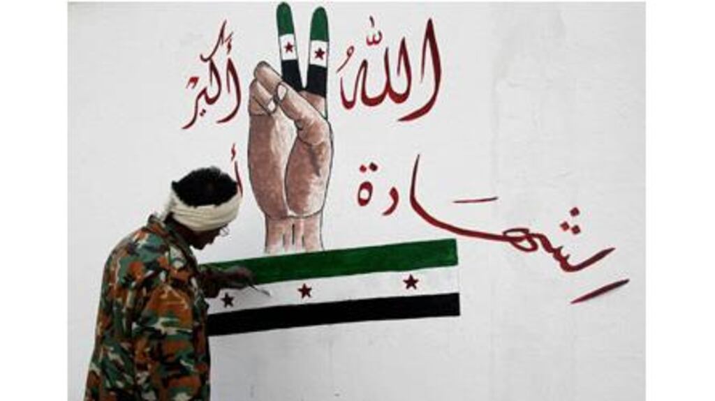 A member of the Free Syrian Army paints on the Al-Moshat school wall in Aleppo yesterday. The drawing reads 'God is great, martyrdom'. Photograph: Muzaffar Salman/Reuters