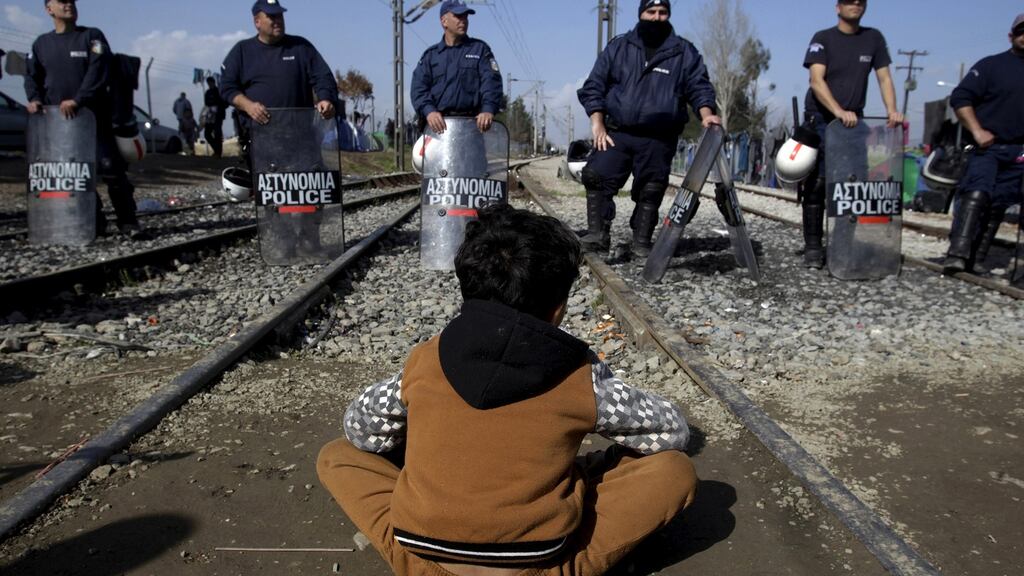 A refugee sits in front of a Greek riot police cordon during a protest at the Greek-Macedonian border. Photograph: Alexandros Avramidis/Reuters