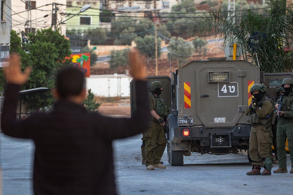 Palestinians walk past armed Israeli soldiers in the village of Al Aqaba. Photograph: Wahaj Bani Moufleh/Middle East Images/AFP via Getty
