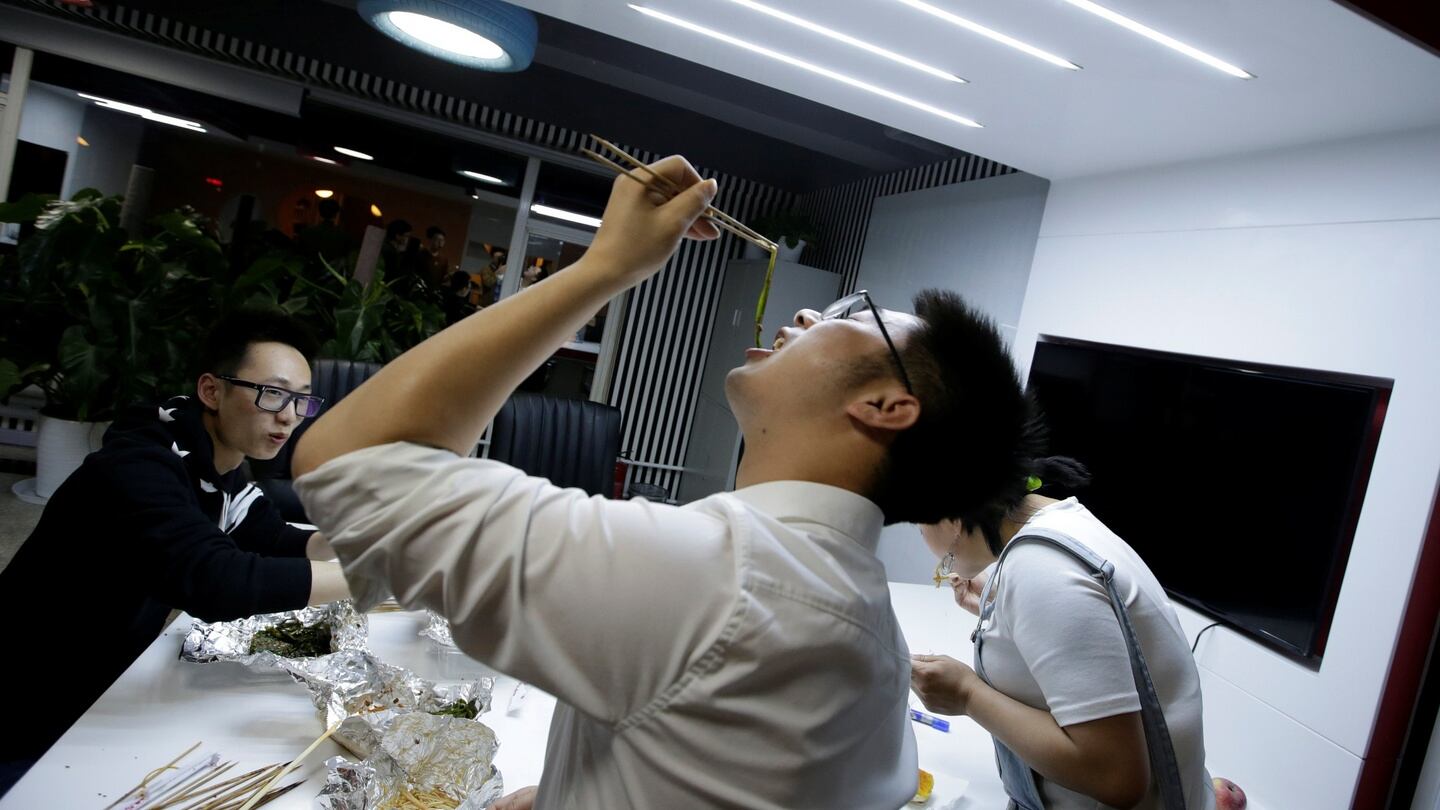 Yu Xiaojian, an employee at Goopal Group, eats with his colleagues during a break at work around midnight. Some companies provide sleeping areas and beds for workers to rest during late nights. Photograph: Jason Lee/Reuters