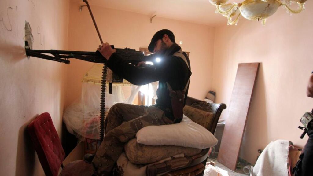A Free Syrian Army fighter takes position inside a room as he points his weapon through a hole in Aleppo's Saif al-Dawla district. Photograph: Reuters