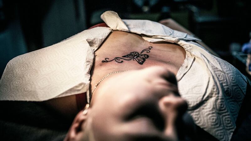 In this photo Viktoria lies on a bed to get a tattoo done to conceal a scar from a domestic violence attack. Photograph: Vadim Braydov/AP