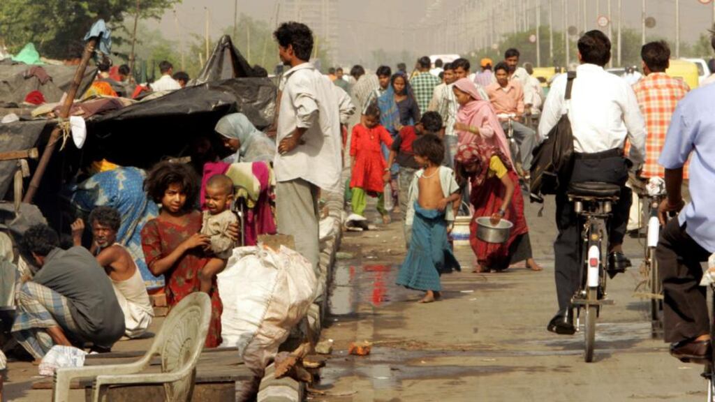 Indian slum dwellers outside their makeshift huts on a roadside in New Delhi. Photograph: Kamal Kishore / Reuters