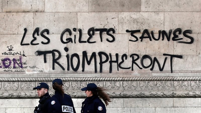 Police officers underneath graffiti sprayed on the side of the Arc de Triomphe in Paris reading “The yellow vests will triumph” as they assess damage after rioting and looting a day earlier. Photograph: Etienne Laurent/EPA