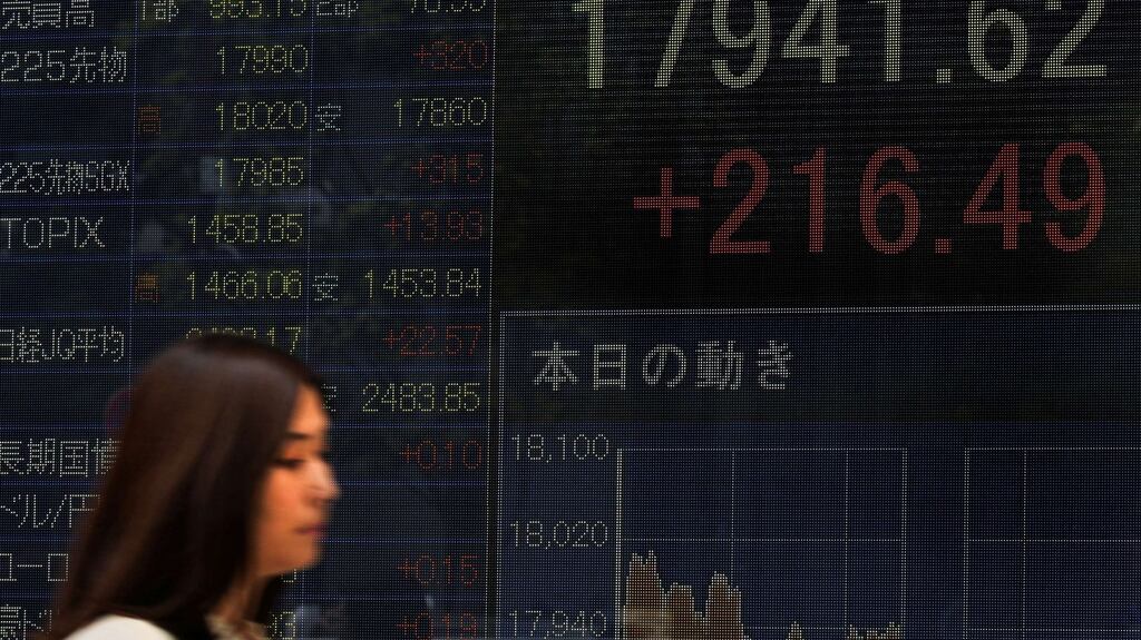 A pedestrian walks past a board flashing the Nikkei key index of the Tokyo Stock Exchange (TSE) in front of a securities company in Tokyo on October 5th, 2015. Tokyo stocks gained 1.22 percent on speculation the US Federal Reserve will keep interest rates near zero for longer and an economic downturn will force Japanese policymakers to increase stimulus. (Photograph: Toru YAMANAKATORU YAMANAKA/AFP/Getty Images)