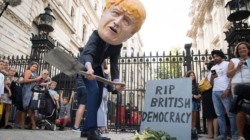 A person wearing a Boris Johnson ‘head’ digs a grave at the foot of a tombstone during a protest outside Downing Street in London on Wednesday. Photograph: Stefan Rousseau/PA Wire