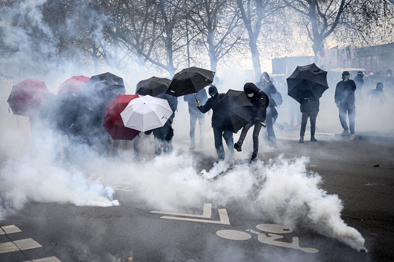 Protestors protect themselves from tear gas with umbrellas during a demonstration in Paris over pension reforms. Photograph: Loic Venance/AFP via Getty Images