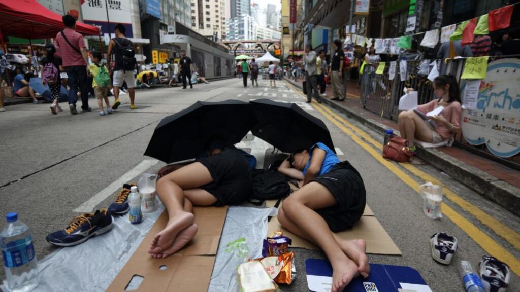 People rest with their heads under umbrellas on a road during a protest in the Causeway Bay area of Hong Kong on Thursday. The Hong Kong government has called for thousands of pro-democracy demonstrators to end their protests and free up the city centre. Photograph: Tomohiro Ohsumi/Bloomberg