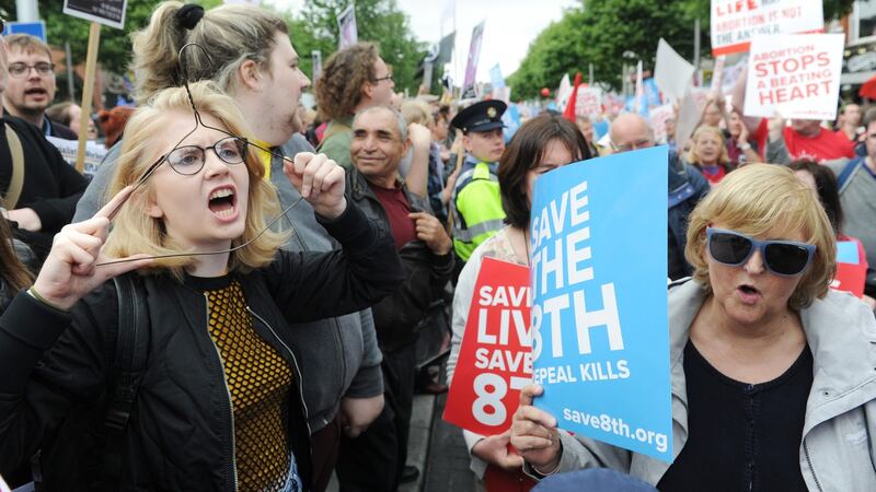 An anti-abortion demonstrator passes a pro-choice protester holding a coat hanger to her face during the march in Dublin. Photograph: Aidan Crawley
