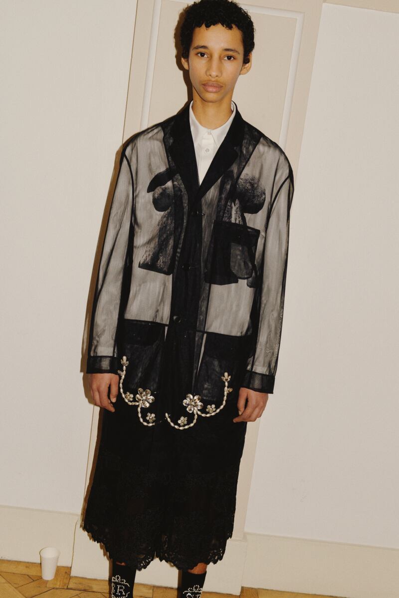 Black tulle overcoat with pearl and crystal embellishment €1605, white cotton poplin shirt with graphic print €455, black corded lace boxing shorts €800, ankle ribbed socks with pearl and crystal embellishment €290