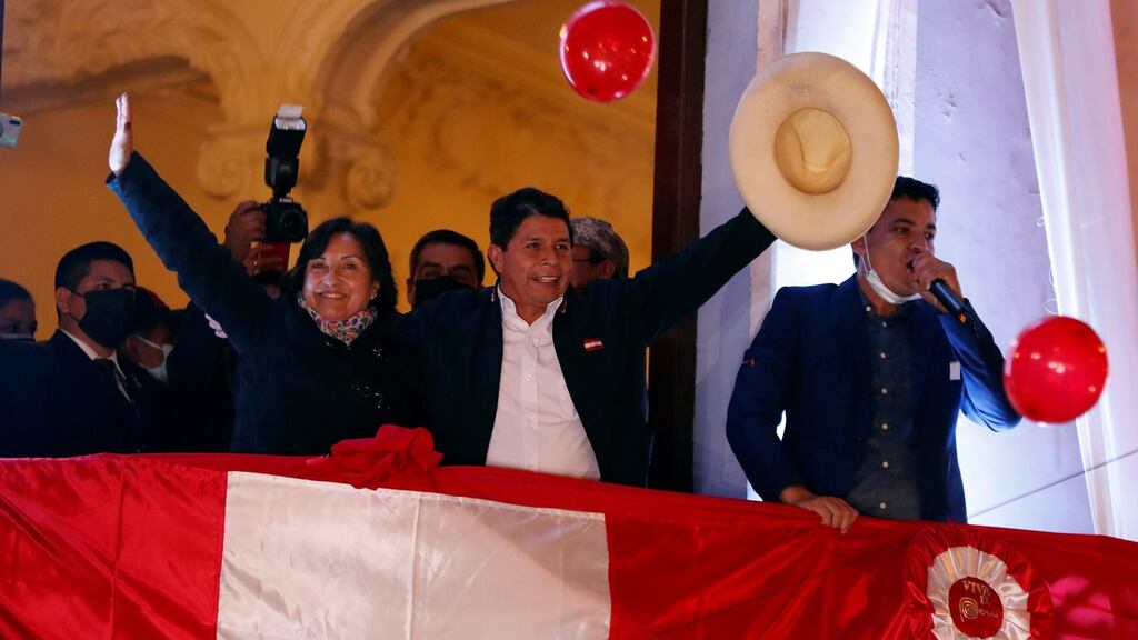 The leftist Pedro Castillo (C), accompanied by his formula to the vice presidency Dina Boluarte (L), greets supporters from a balcony after being proclaimed president-elect of the country. Photograph: Paolo Aguilar/EPA
