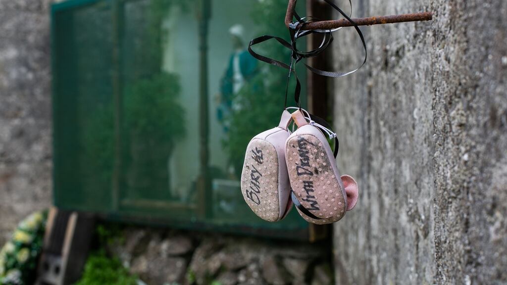 A pair of baby shoes with the message ‘Bury us with dignity’ hangs on a wall at the site of the Tuam mother-and-baby home. Photograph: Andy Newman