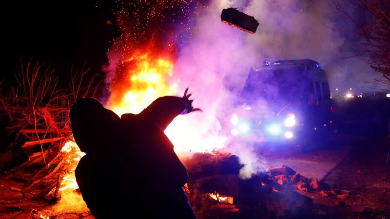 A demonstrator throws a stone towards a police van during a protest against the arrival of a plane carrying evacuees from China’s Hubei province in the village of Novi Sanzhary, Ukraine on Thursday. Photograph: Valentyn Ogirenko/Reuters