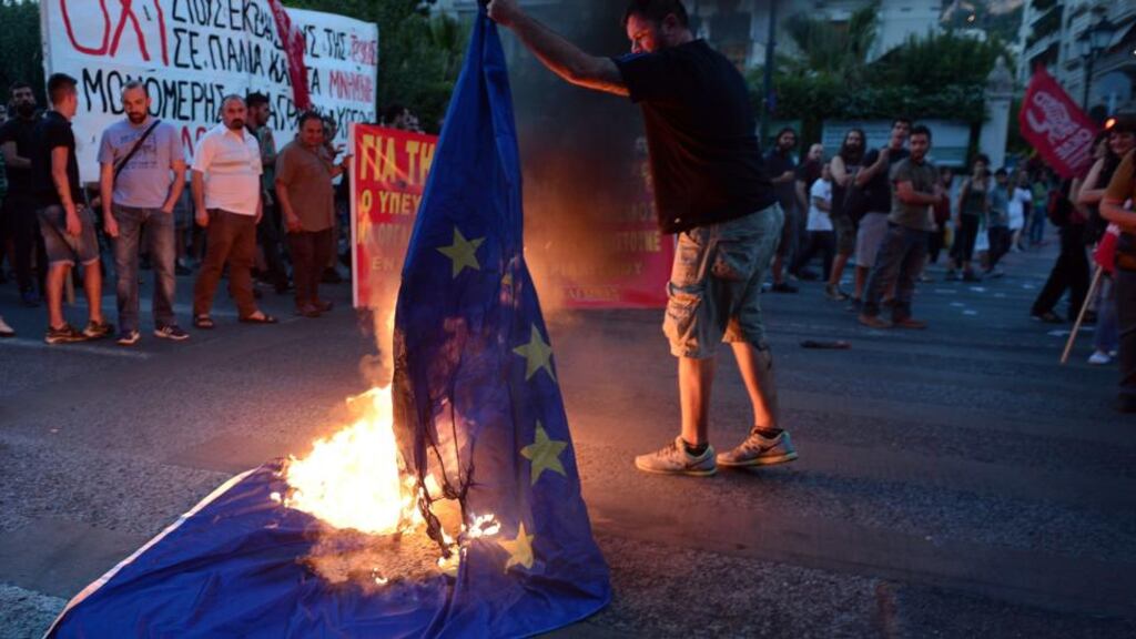 An anti-EU protester burns an EU flag in front of the European Comission offices in Athens on July 2. Photograph: AFP PHOTO / Louisa Gouliamaki