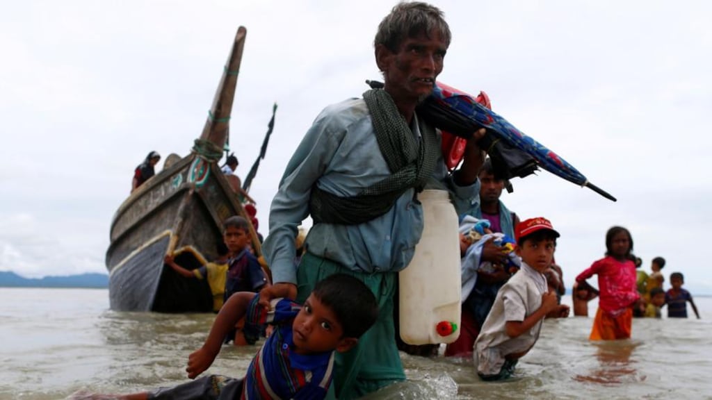 A Rohingya refugee man pulls a child as they walk to the shore after crossing the Bangladesh-Myanmar border by boat through the Bay of Bengal in Shah Porir Dwip, Bangladesh. Photograph: Reuters/Danish Siddiqui