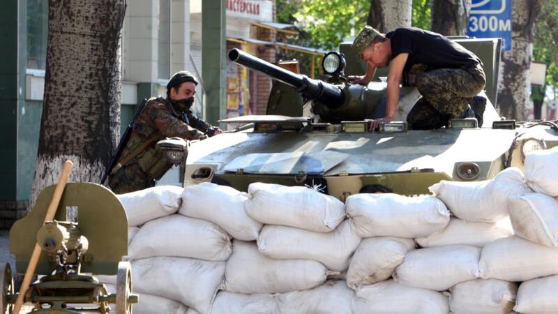 Pro-Russian militia work on an armoured vehicle behind a sandbag barrier near an occupied security service building in Slaviansk, Ukraine. Photograph: Igor Kovalenko/EPA