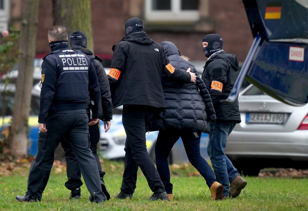 A suspect is escorted from a police helicopter by police officers after the arrival for a questioning after raids across much of Germany against suspected far-right extremists. Photograph: Michael Probst/AP/PA