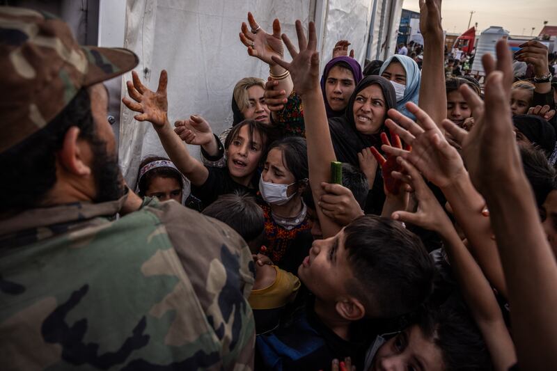 A Taliban official hands out bags of cucumber to Afghan refugees at reception centre in the border town of Islam Qala, Afghanistan. Photograph: Jim Huylebroek/The New York Times