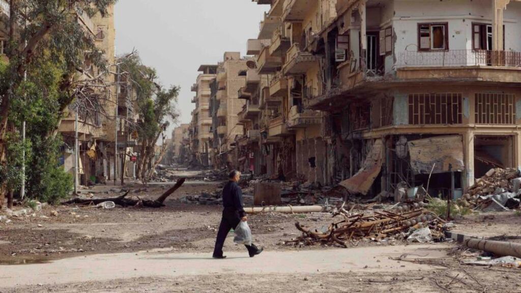 A man walks past damaged houses on a street filled with debris in Deir al-Zor, Syria. Photograph: Reuters